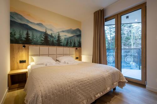 a bedroom with a large bed and a large window at Apartamenty Beski in Szczyrk