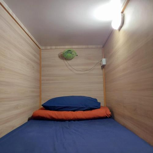 a small bed in a small room with a wall at BRICKS Backpackers Sleepbox in Tanah Rata