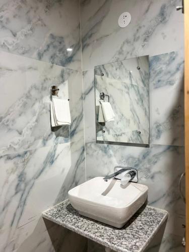 a white bathroom with a sink and a mirror at Liora Stays in Palchān
