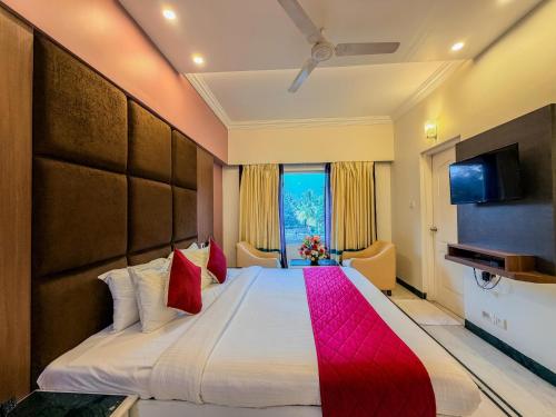 a hotel room with a large bed with red pillows at Zip By Spree Hotels Surabi International Vellore in Vellore