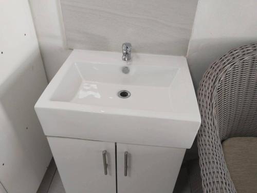 a bathroom with a white sink and a chair at Memories Vaaldam in Denysville