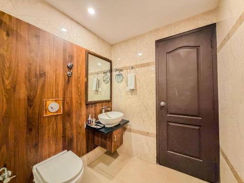 a bathroom with a toilet and a sink and a mirror at Zip By Spree Hotels Surabi International Vellore in Vellore