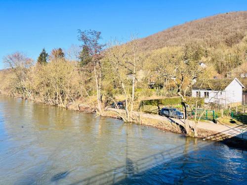 a river with cars parked on the side of it at Riverside Cabin Surrounded by Nature for Two in Esneux