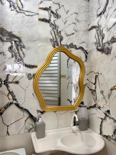 a bathroom with a gold framed mirror over a sink at Apartamento no Centro in Manaus