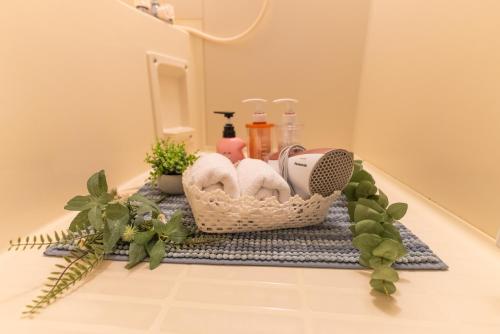 a basket with towels and other items on a bathroom counter at Guest House Kubo Homes Tanimachi in Osaka