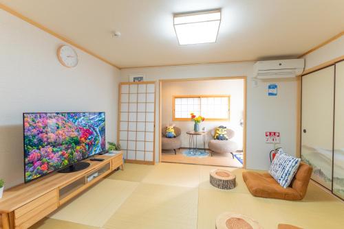 a living room with a large flat screen tv at Guest House Kubo Homes Tanimachi in Osaka