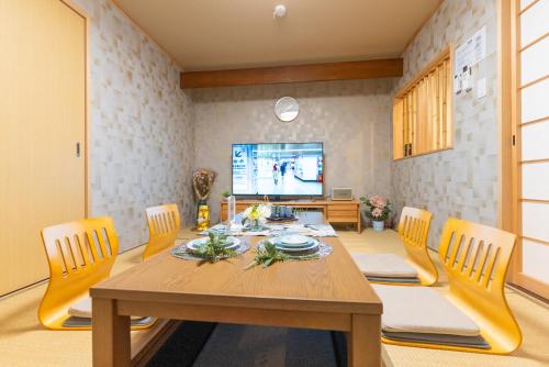 a dining room with a table and chairs and a television at Guest House Kubo Homes Tanimachi in Osaka
