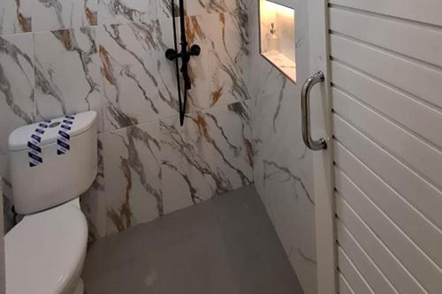 a bathroom with a toilet and a marble wall at Sultan Guest House in Palu