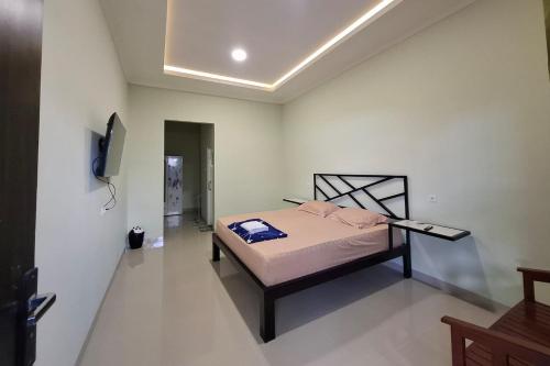 a bedroom with a bed and a tv on a wall at Sultan Guest House in Palu