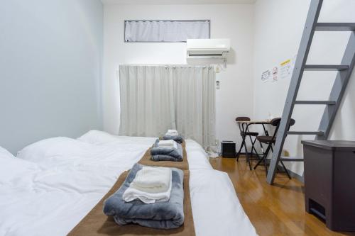 a room with three beds with towels on them at Kaizuka Good Place House in Fukuoka