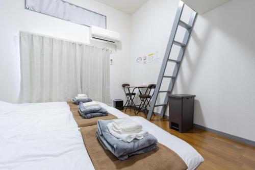 two beds in a room with a ladder at Kaizuka Good Place House in Fukuoka