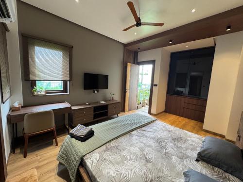 a bedroom with a bed and a desk and a television at Skywood Villa Rooms in Lucknow