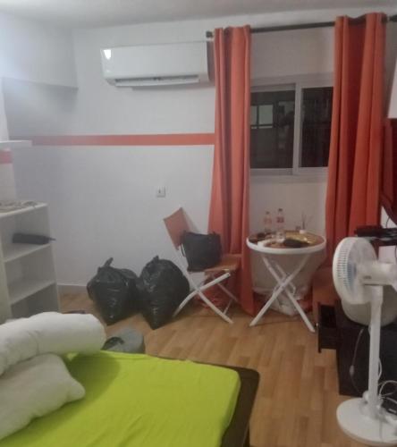 un soggiorno con un letto, un tavolo e delle sedie di Chris a Abidjan