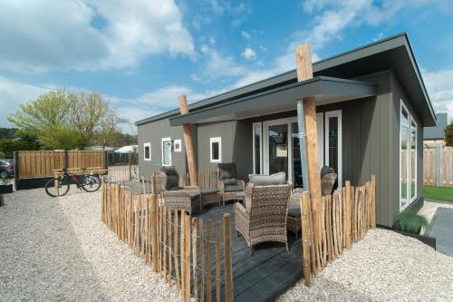 a tiny house with a porch and chairs at Bungalowverhuur 't Lappennest in Noordwijk