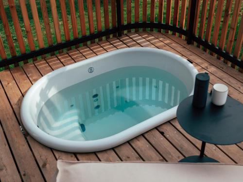 a bath tub sitting on a deck with a table at Hapfn Tiny Houses mit Hot Tub in Eibiswald