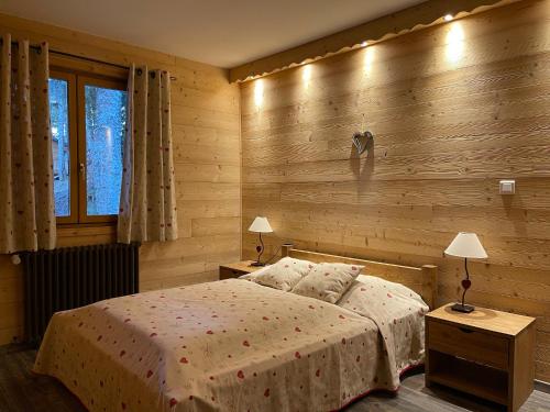 a bedroom with a bed and a wooden wall at LE SAPORTA- Studios et Appartements meublés de tourisme in Le Lioran
