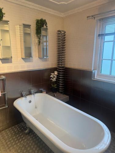 a large white tub in a bathroom with a window at Sea View House in Dalkeith