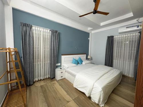 a bedroom with a white bed and blue walls at Evania Pool Suites in Nedumbassery