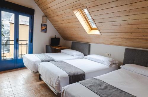 a room with three beds and a skylight at Hostal Nau Pradets in Vielha