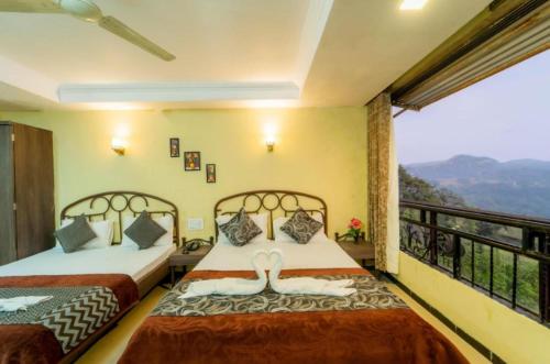 two beds in a room with a balcony at Hotel Indira Nature Valley Mahabaleshwar in Mahabaleshwar