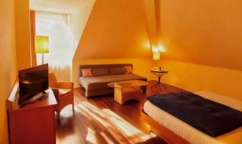 a room with a bed and a couch and a tv at Hotel Ambiente in Dortmund