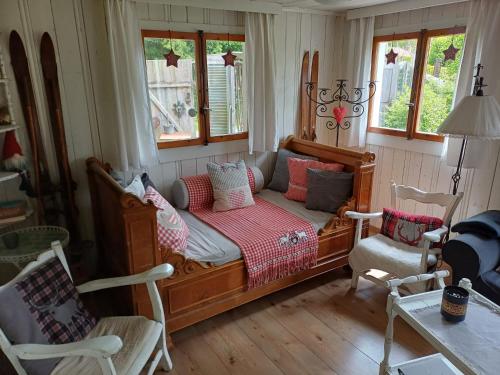 a bedroom with a bed and two chairs and windows at Chalet Chic mit Hot Pot in Wildhaus