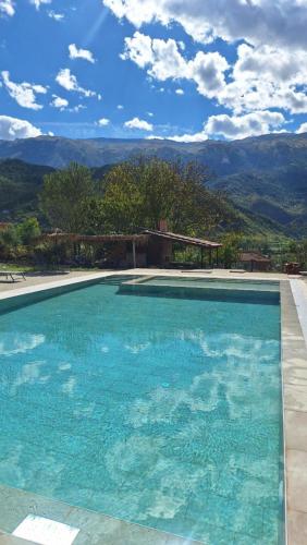 a large blue swimming pool with mountains in the background at Guesthouse Lumo & pool in Përmet