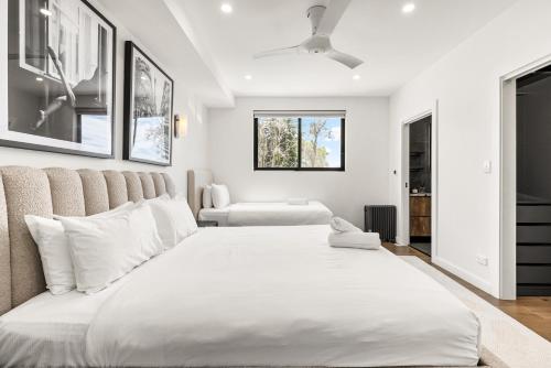 a white bedroom with a large bed and a window at Group & Family 3BR with Game Room, Terrace & Parking in Sydney