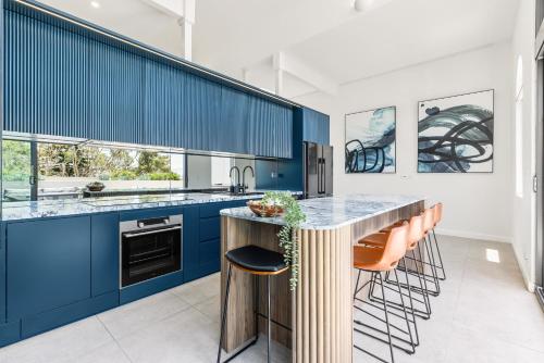 a kitchen with blue cabinets and orange bar stools at Group & Family 3BR with Game Room, Terrace & Parking in Sydney