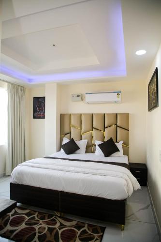 a bedroom with a large white bed with black pillows at The Manor Inn in Phagwāra