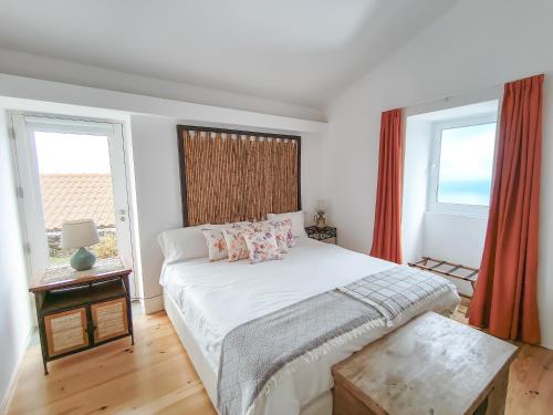 a bedroom with a bed and two windows at Casa da Delonga in Nordeste
