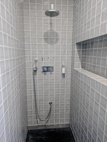 a white tiled bathroom with a shower with a mirror at Casa da Delonga in Nordeste