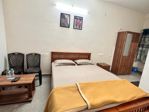 a bedroom with a bed and a table and a chair at Dhruvanish Grand in Sringeri