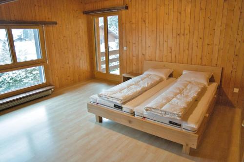 a bed in a room with wooden walls and windows at Haus Panorama in Schwarzsee