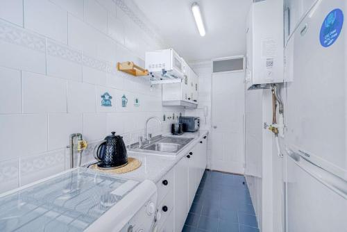 a white kitchen with a tea kettle on the counter at Costa Azul- 3D Seafront Apartment in Algarrobo