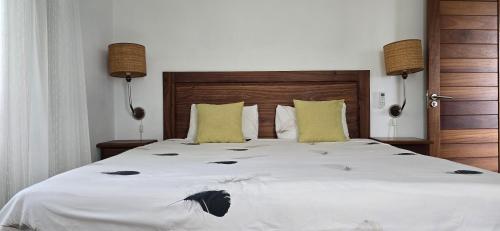 a bedroom with a large white bed with yellow pillows at Villa Trochetia in La Gaulette