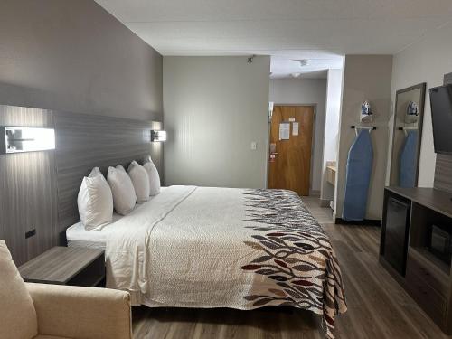 a hotel room with a large bed and a couch at Red Roof Inn & Suites Middleborough in Middleboro