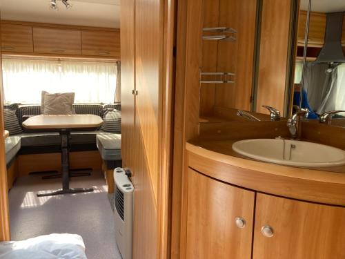 a bathroom with a sink and a table and a couch at Mietwohnwagen E2 am Flussufer in Wienhausen