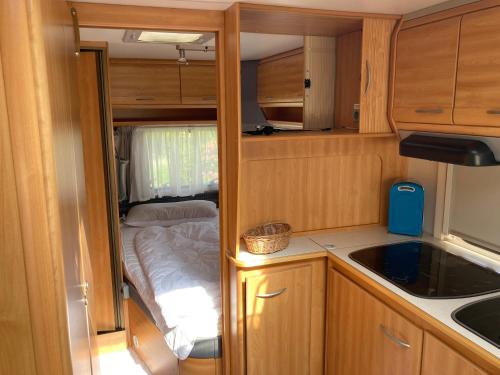 a small kitchen with a bed in an rv at Mietwohnwagen E2 am Flussufer in Wienhausen