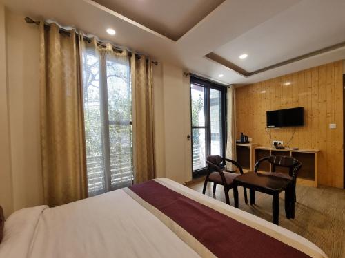 a bedroom with a bed and a desk and a television at Nomad Uber Hotel - Near Mall Road Dalhousie in Dalhousie