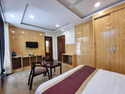a hotel room with a bed and a desk and a tv at Nomad Uber Hotel - Near Mall Road Dalhousie in Dalhousie