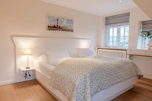 a white bedroom with a bed and a window at Friesenliebe in Borgsum