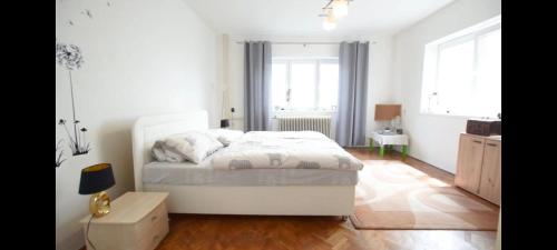 a bedroom with a white bed and a table and windows at Pension Paradise Slowakia in Pastovce
