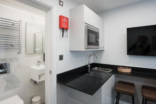 a white bathroom with a sink and a tv at MSK The Whiteley in London