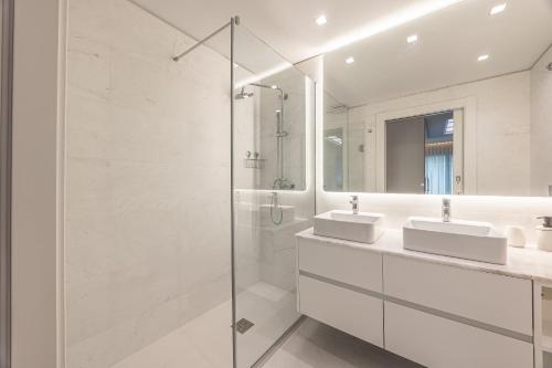a white bathroom with two sinks and a shower at Acqua Residence in Funchal