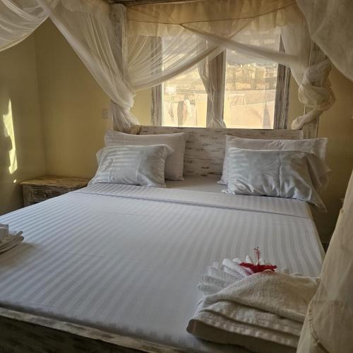 a large white bed with a window in a bedroom at Orange apartment 1 in Watamu