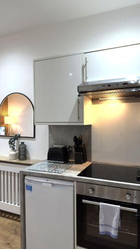 a kitchen with white cabinets and a stove top oven at Modern apartment in Edinburgh in Edinburgh