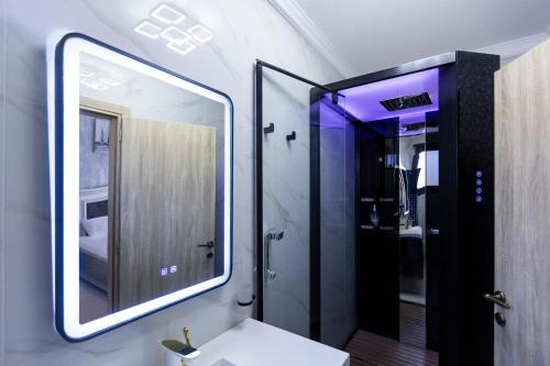 a bathroom with a mirror and a sink and a shower at Adonis Resort & Spa in Egina