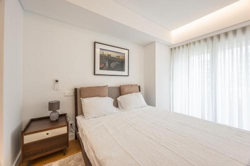 a white bedroom with a bed and a window at Acqua Residence in Funchal