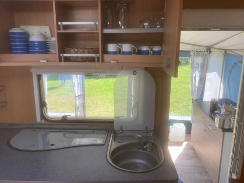 a kitchen with a sink and a window in a caravan at Mietwohnwagen S1 am Flussufer in Wienhausen